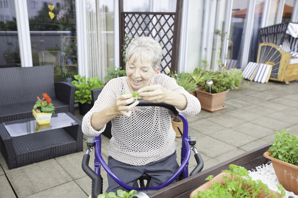 Bewohnerin bei einer Aktivität auf der bepflanzten Terrasse